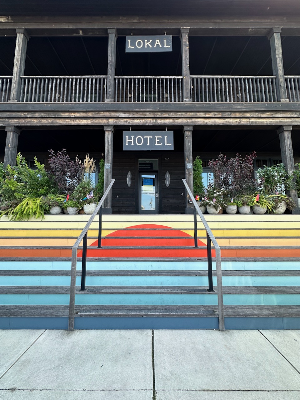 Two-story wooden hotel with front steps painted to look like the sun rising over the ocean.