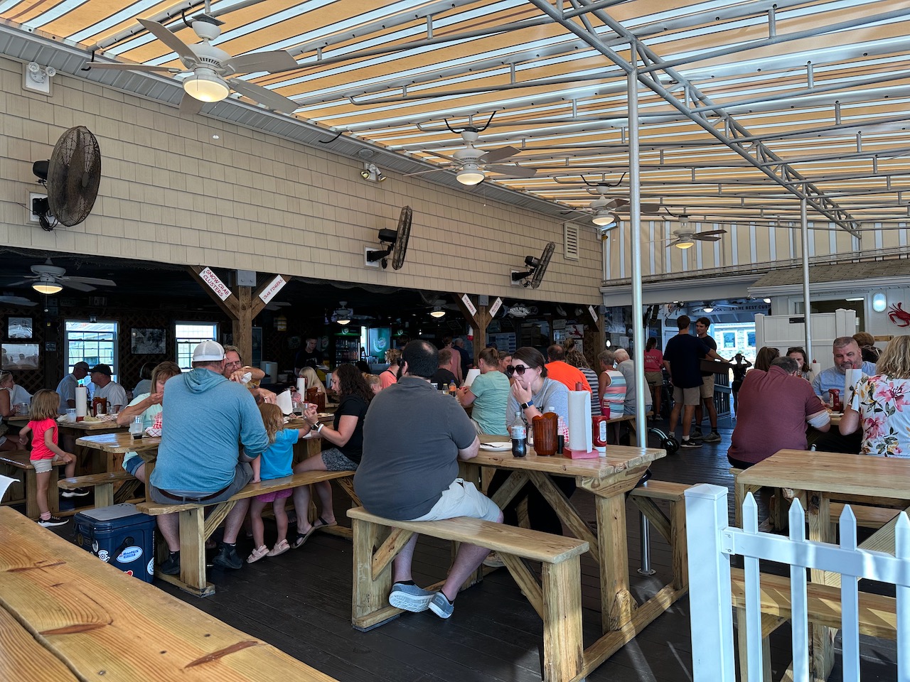 Interior of Dock Mike's, with people sitting on wooden tables beneath an awning.