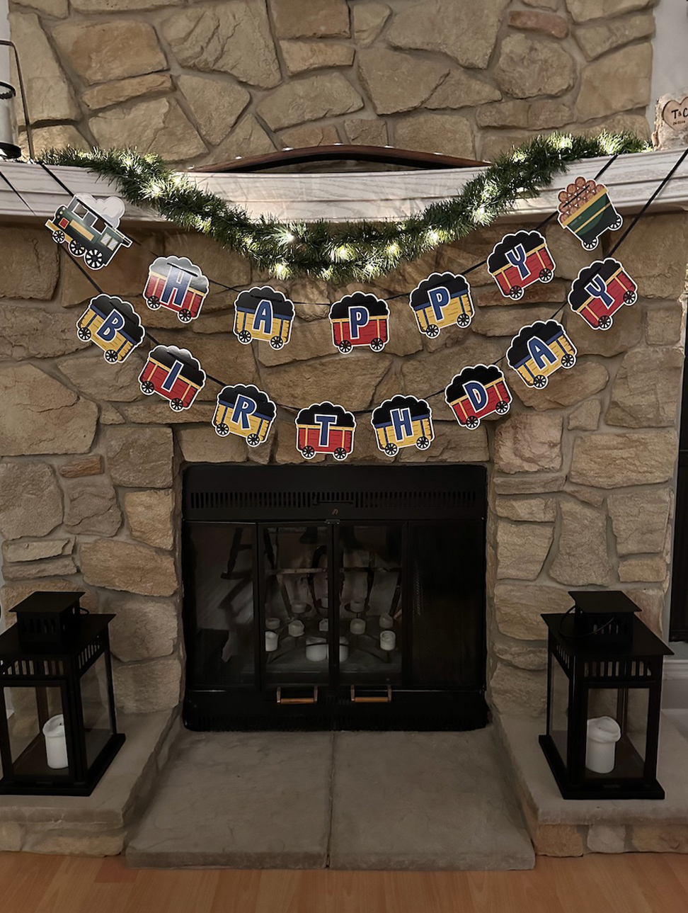 Fireplace with banner that spells out HAPPY BIRTHDAY on pictures of railroad cars.