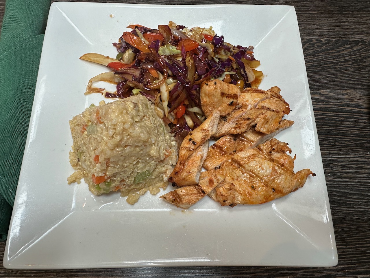 Chicken, vegetables, and rice on white plate.