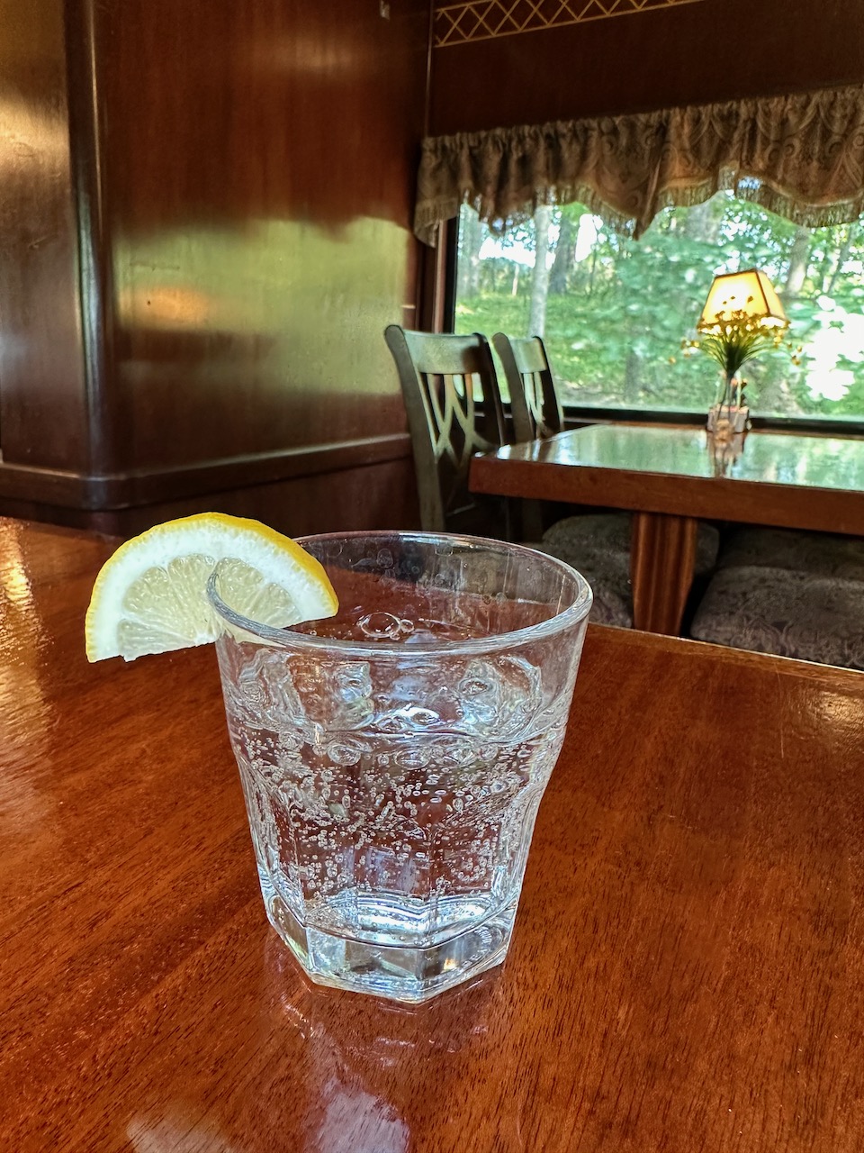 Club soda with lemon in glass, on table.