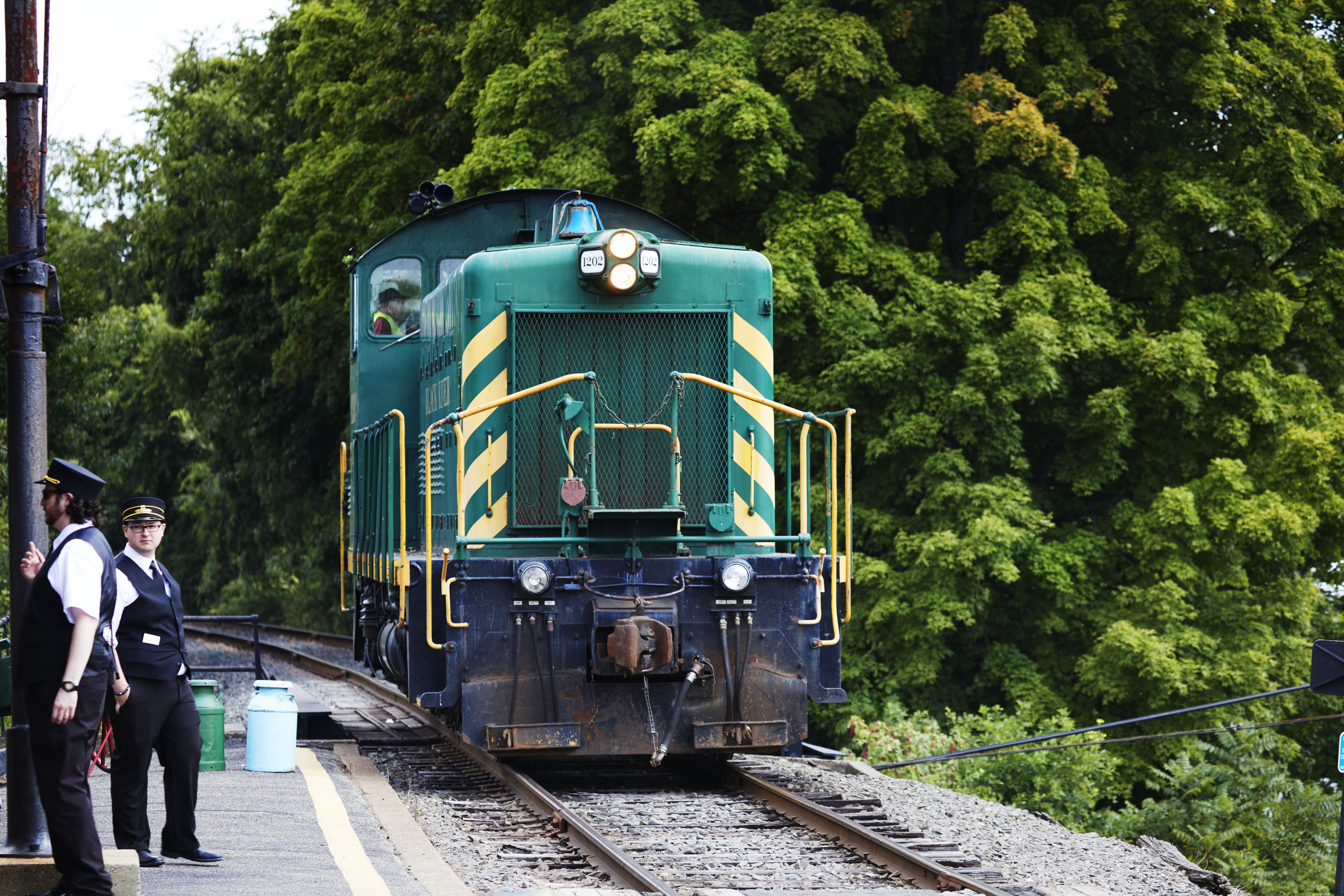PRR 9206 locomotive on tracks. Conductors stand on station platform.