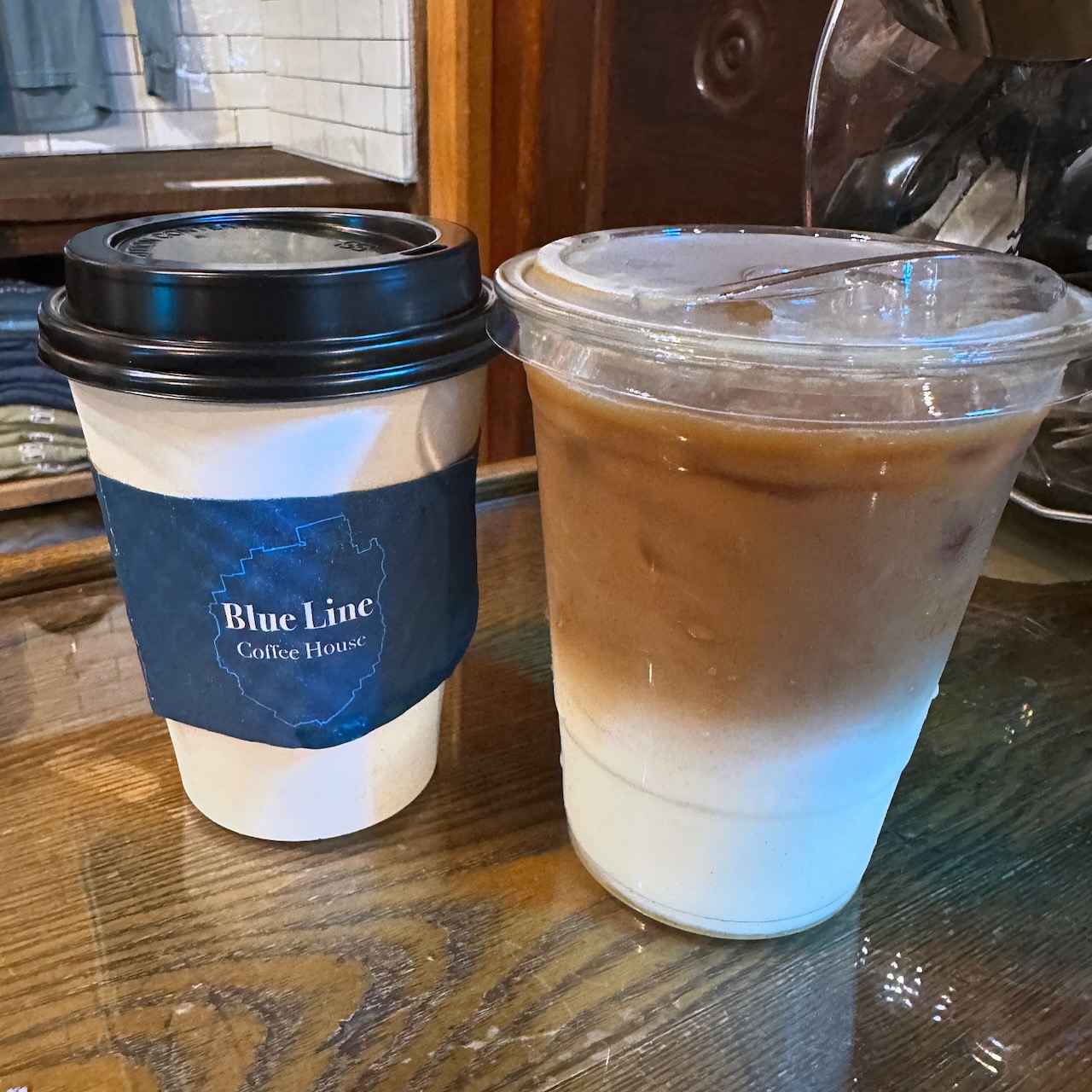 Iced coffee and hot latte on wooden tabletop.