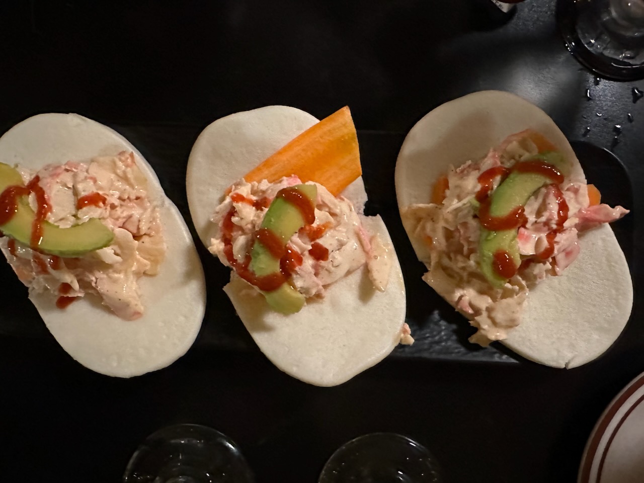 Bao buns filled with crabmeat on black plate.