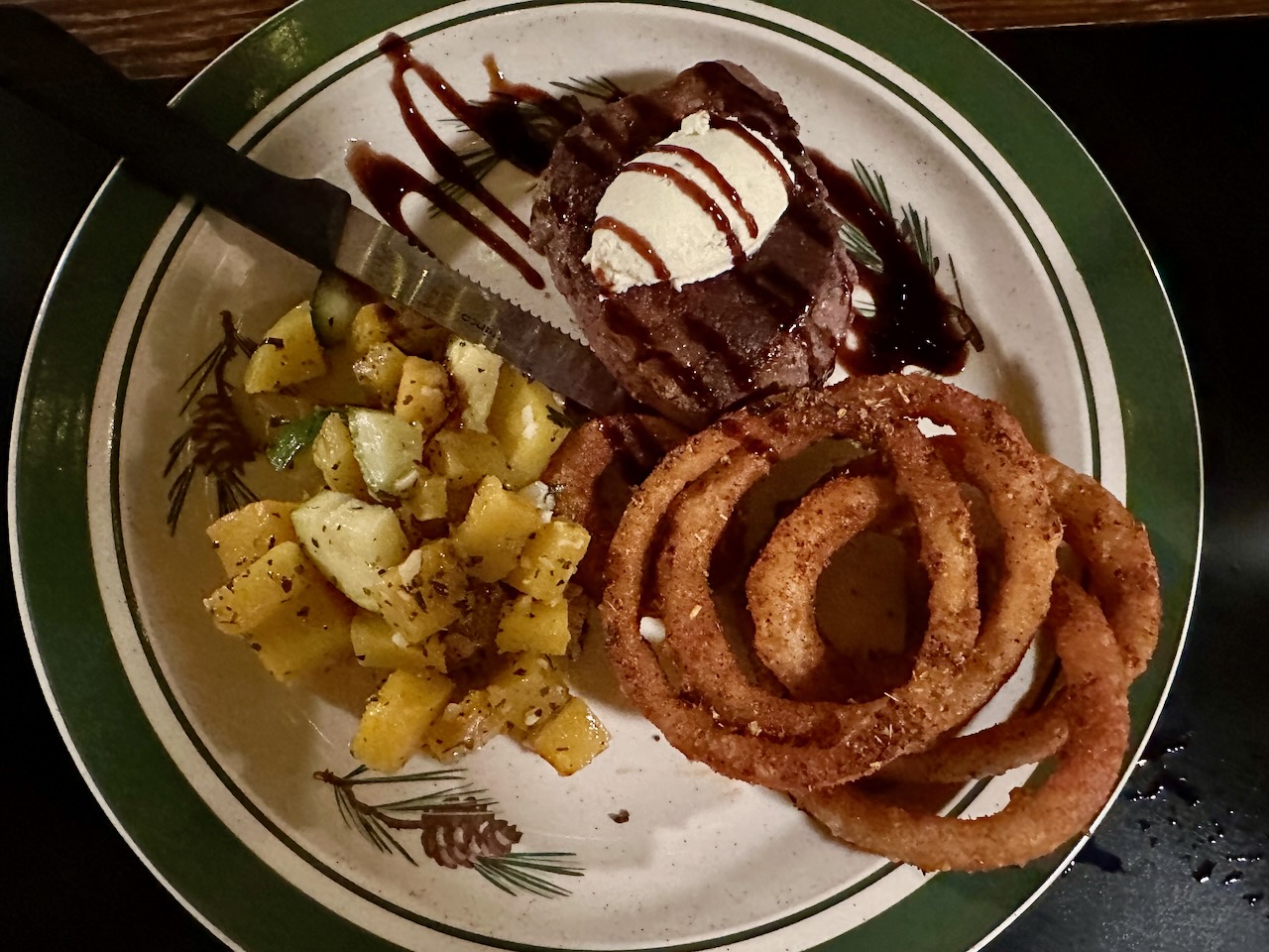 Steak, potatoes, and onion rings on plate.