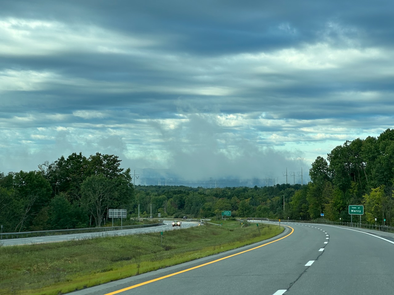 Low-hanging mist over treelike. A highway is in the foreground.