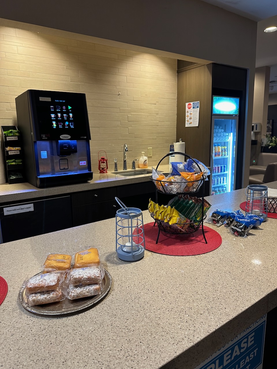 Snacks on counter, with coffee maker and refrigerator against far wall.