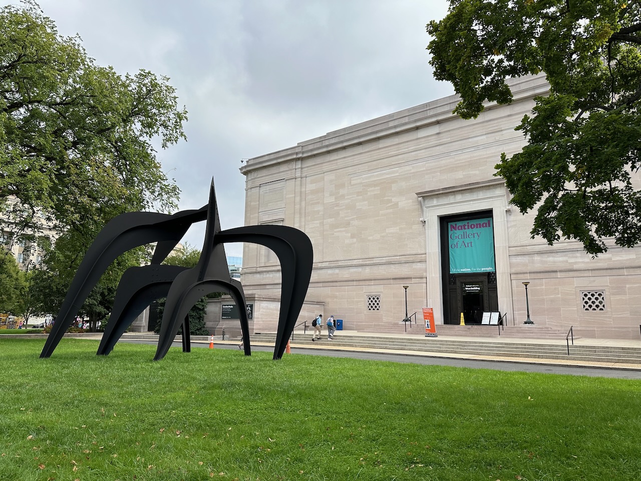 Exterior of National Gallery of Art with spider sculpture in lawn.
