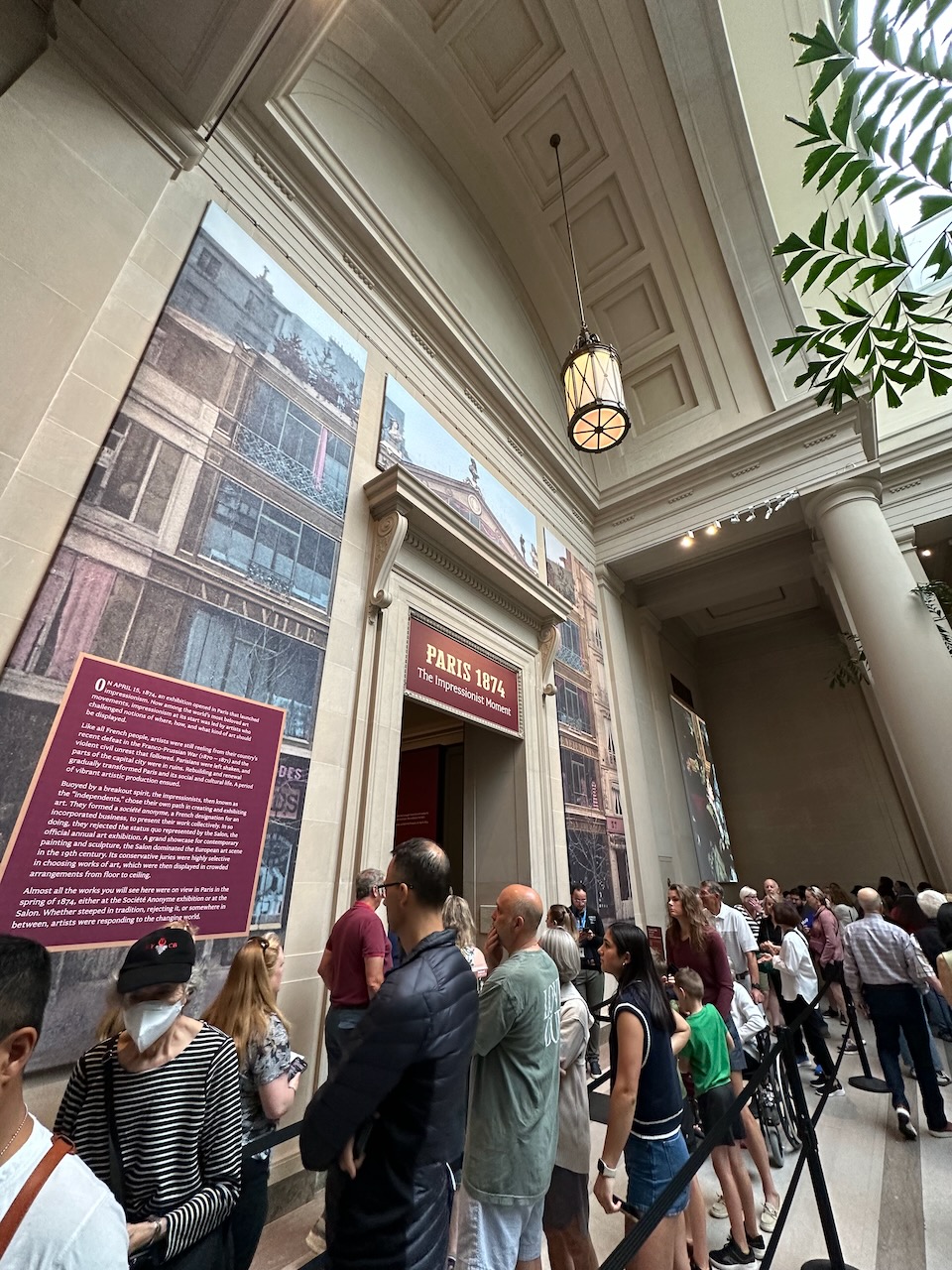 Entrance to gallery with Paris 1874 exhibition, with line of people waiting for entrance.