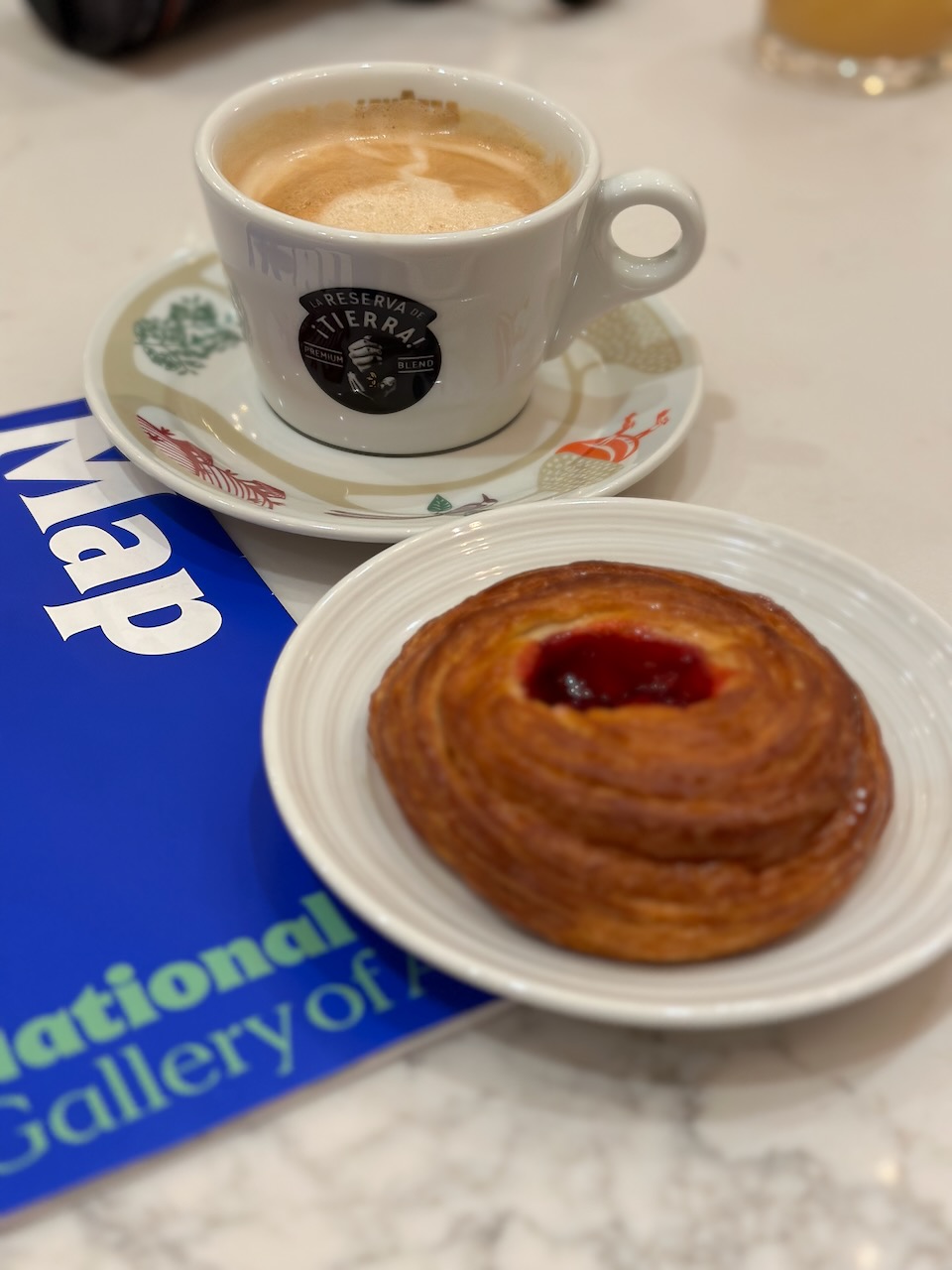 Latte in white cup and danish on white plate.