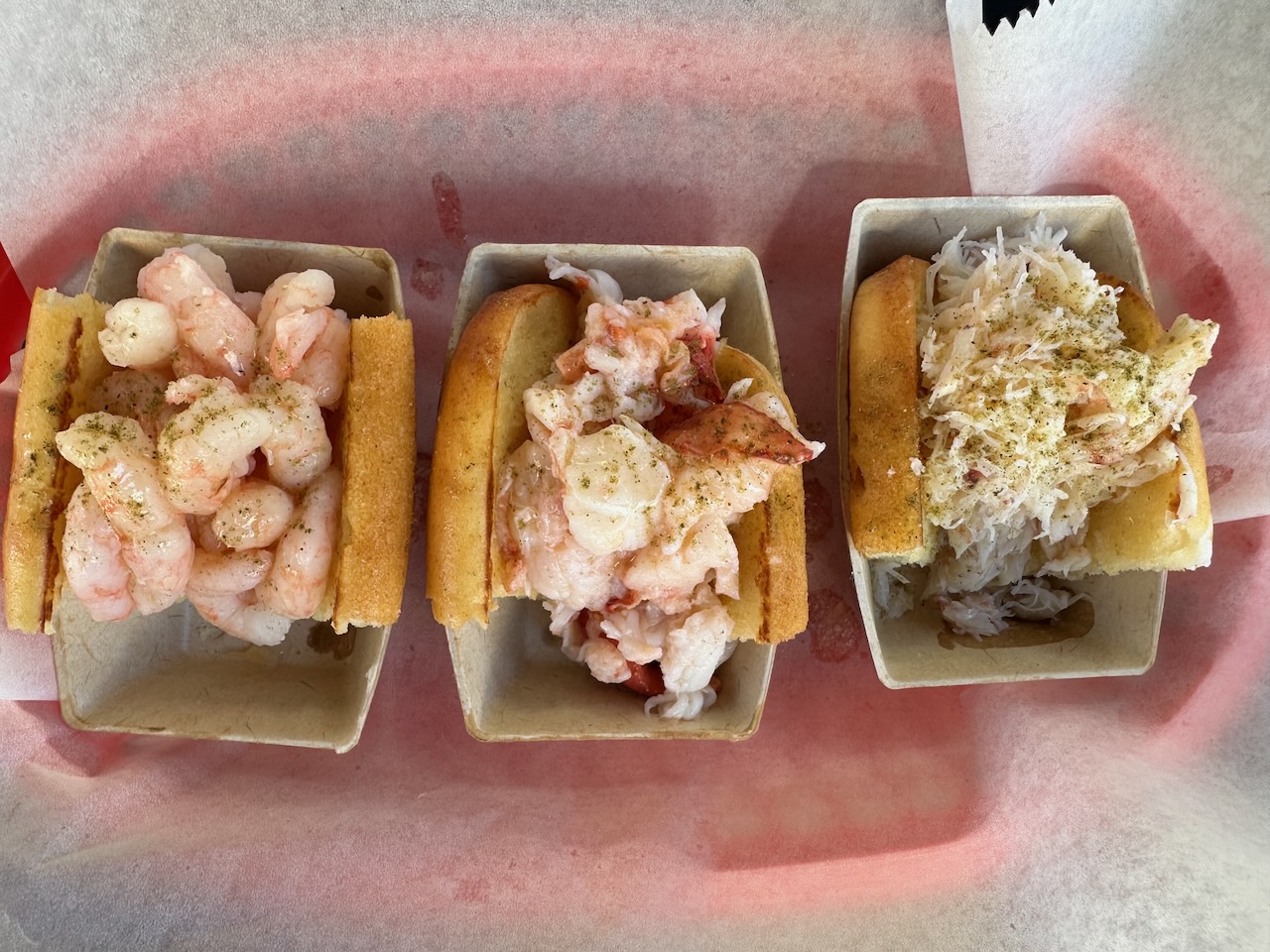 Three buns, one filled with crab meat, one with lobster meat, and one with shrimp. The buns are in a basket.