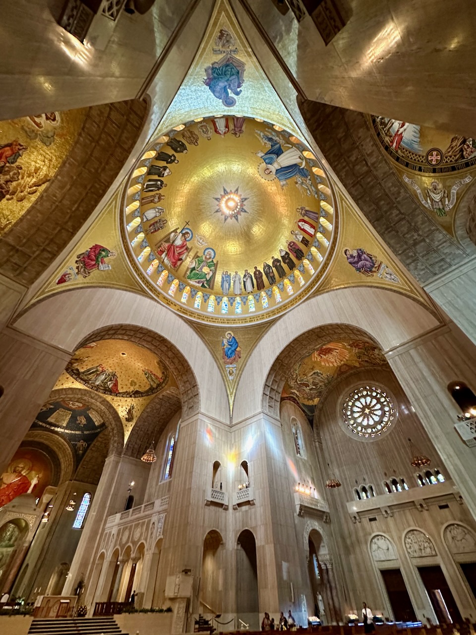View of ceiling of basilica, with dome in center of image with inlaid mosaics.