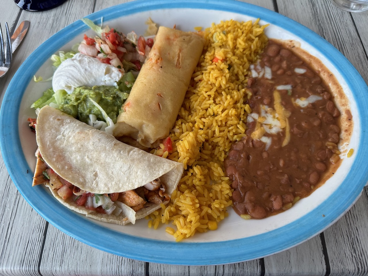 Plate with taco, tamale, refried beans, and rice.