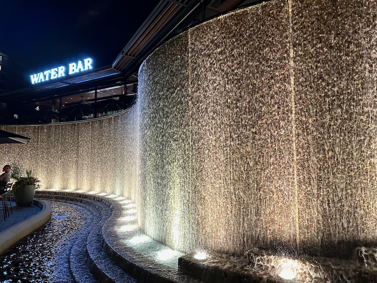 View of man-made waterfall, with words WATER BAR above the waterfall.
