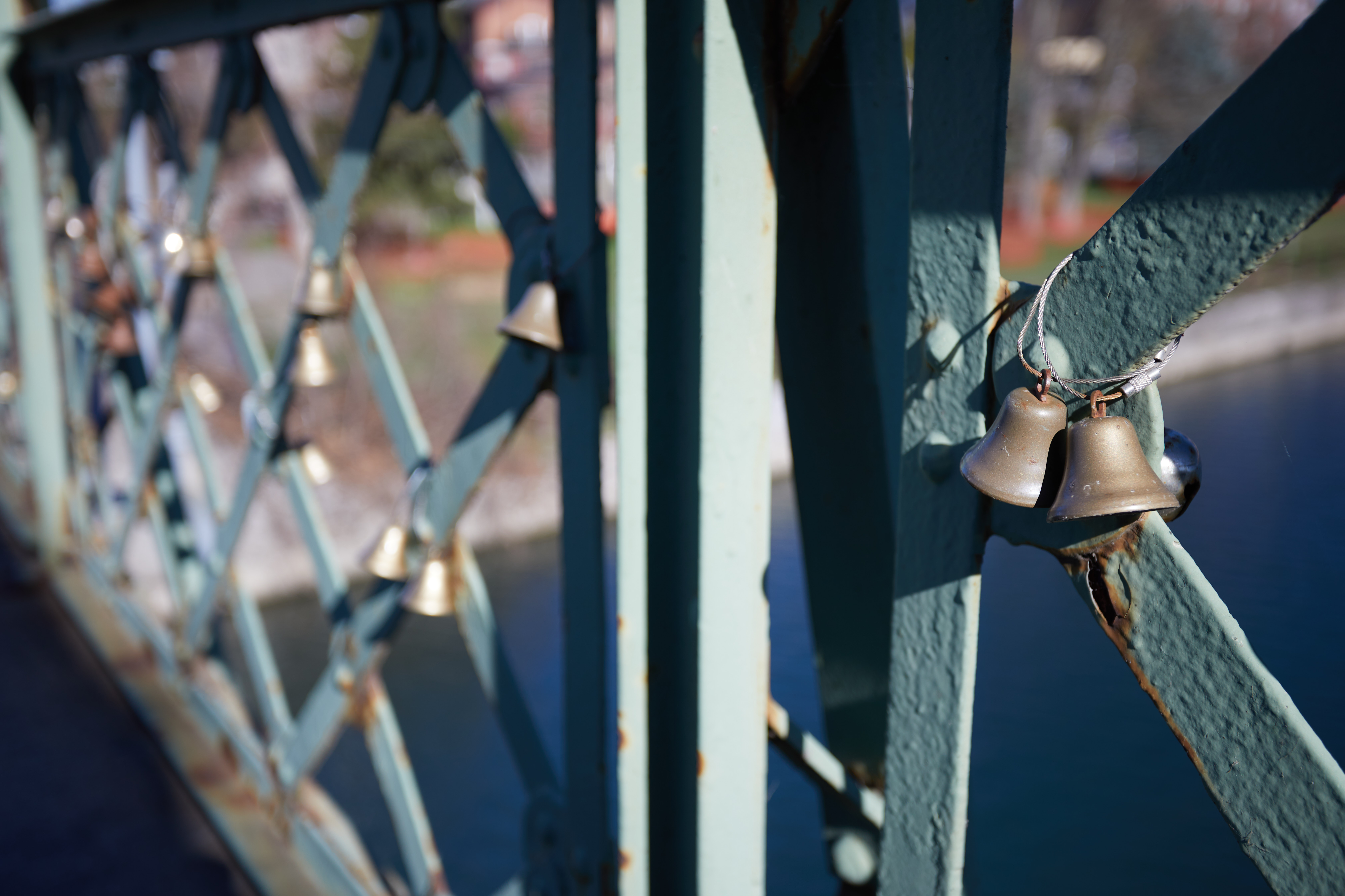 Bells affixed to side of bridge railing.
