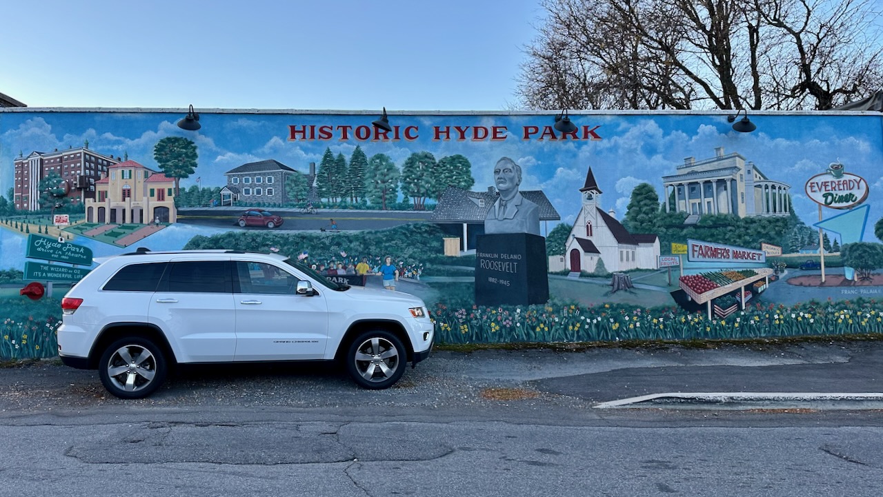 2014 Jeep Grand Cherokee parked in front of mural of Hyde Park on side of building.
