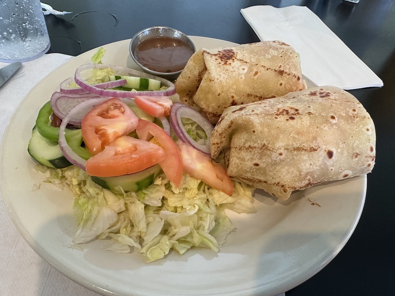 Chicken sandwich wrap on white plate with side salad.