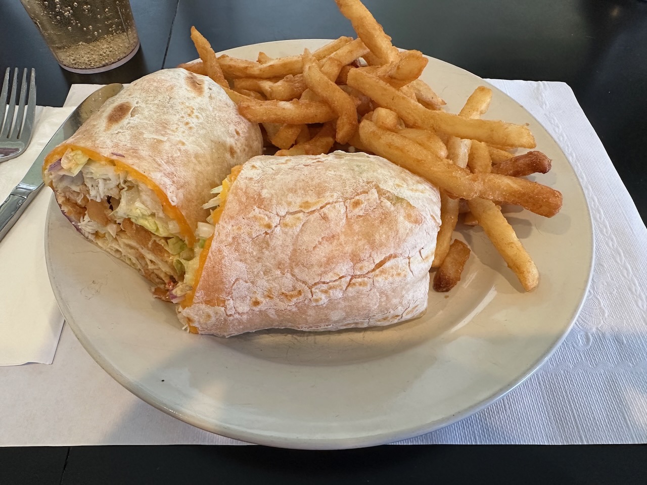 Chicken sandwich wrap on plate with french fries.