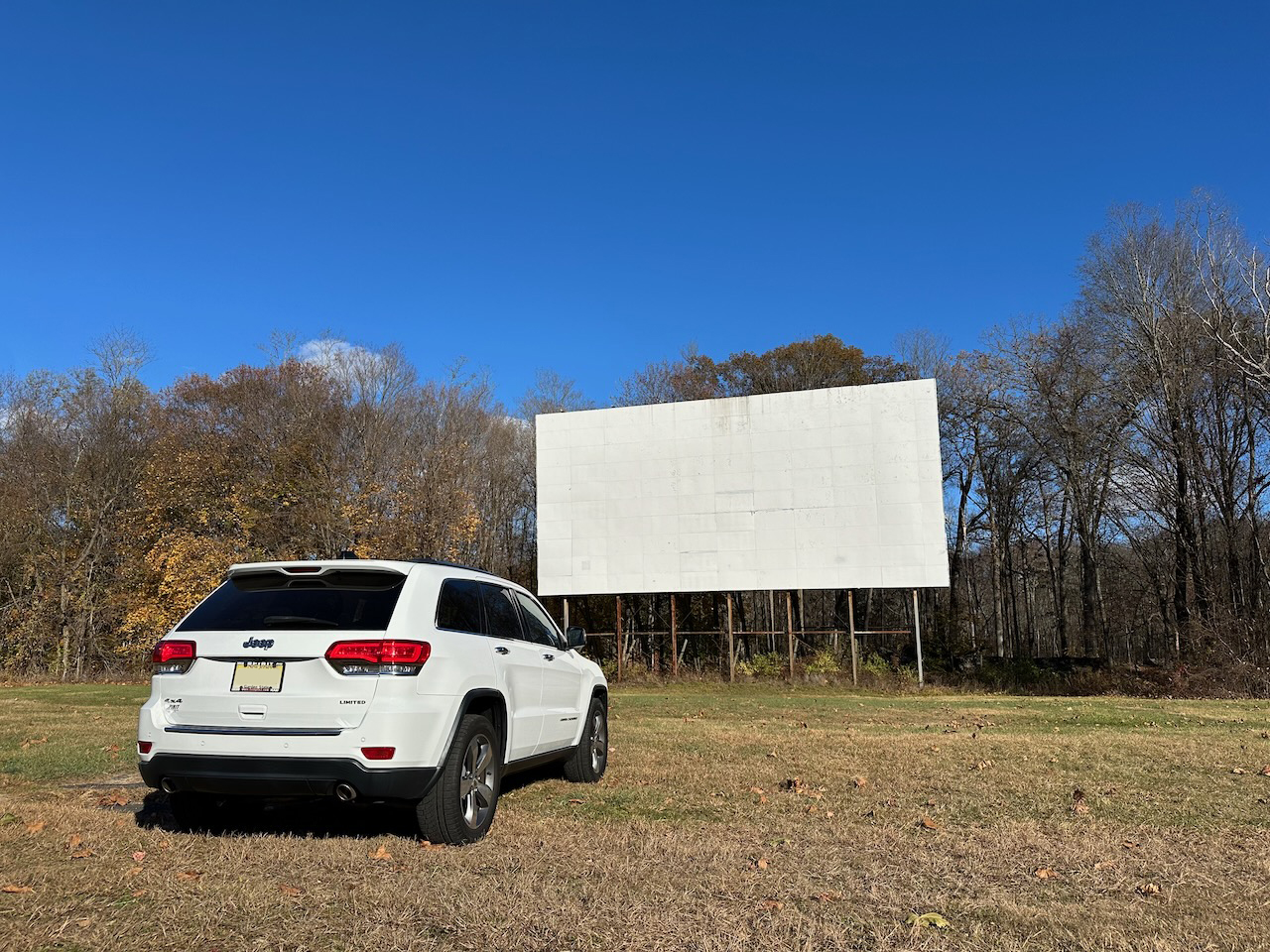 2014 Jeep Grand Cherokee parked in front of drive-in movie theater screen.