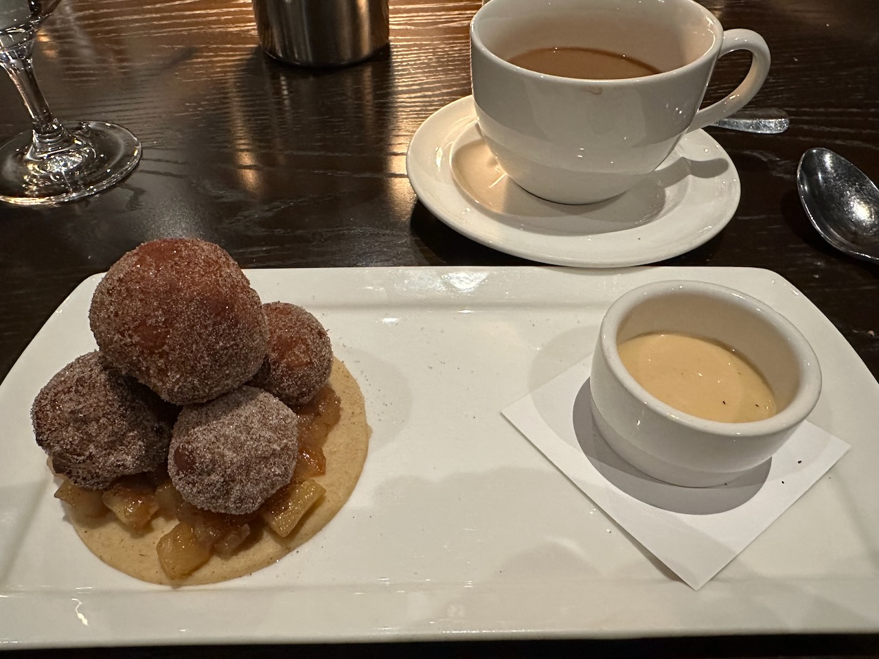 Donut holes and vanilla sauce on white plate.