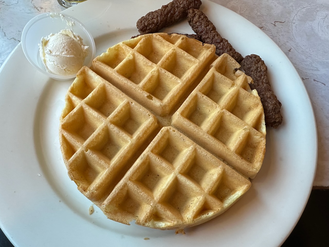 Waffle and sausage on white plate.