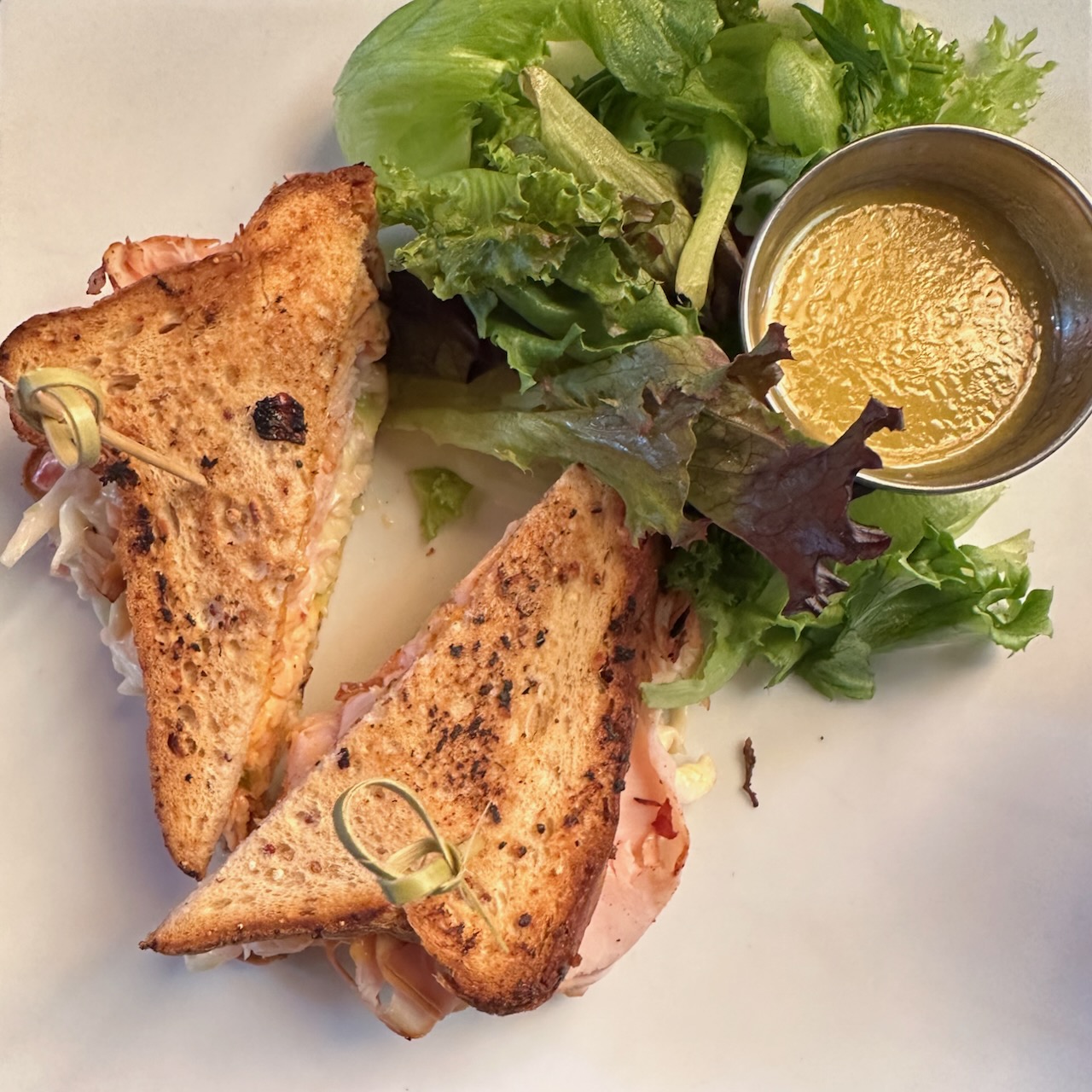 Turkey reuben on gluten free toast beside a salad, all on a white plate.
