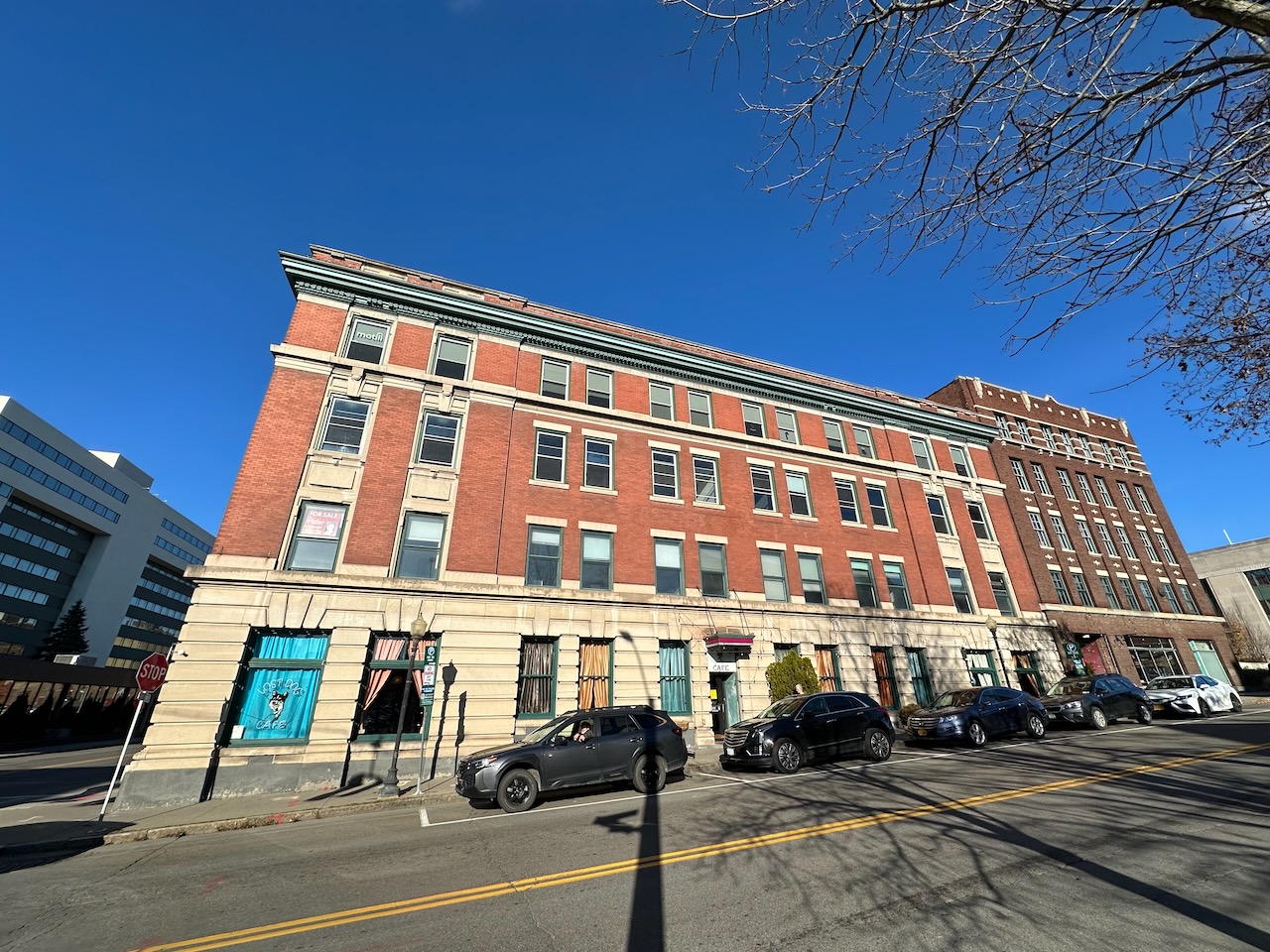 Large brick building with cars parked in street in front of it.