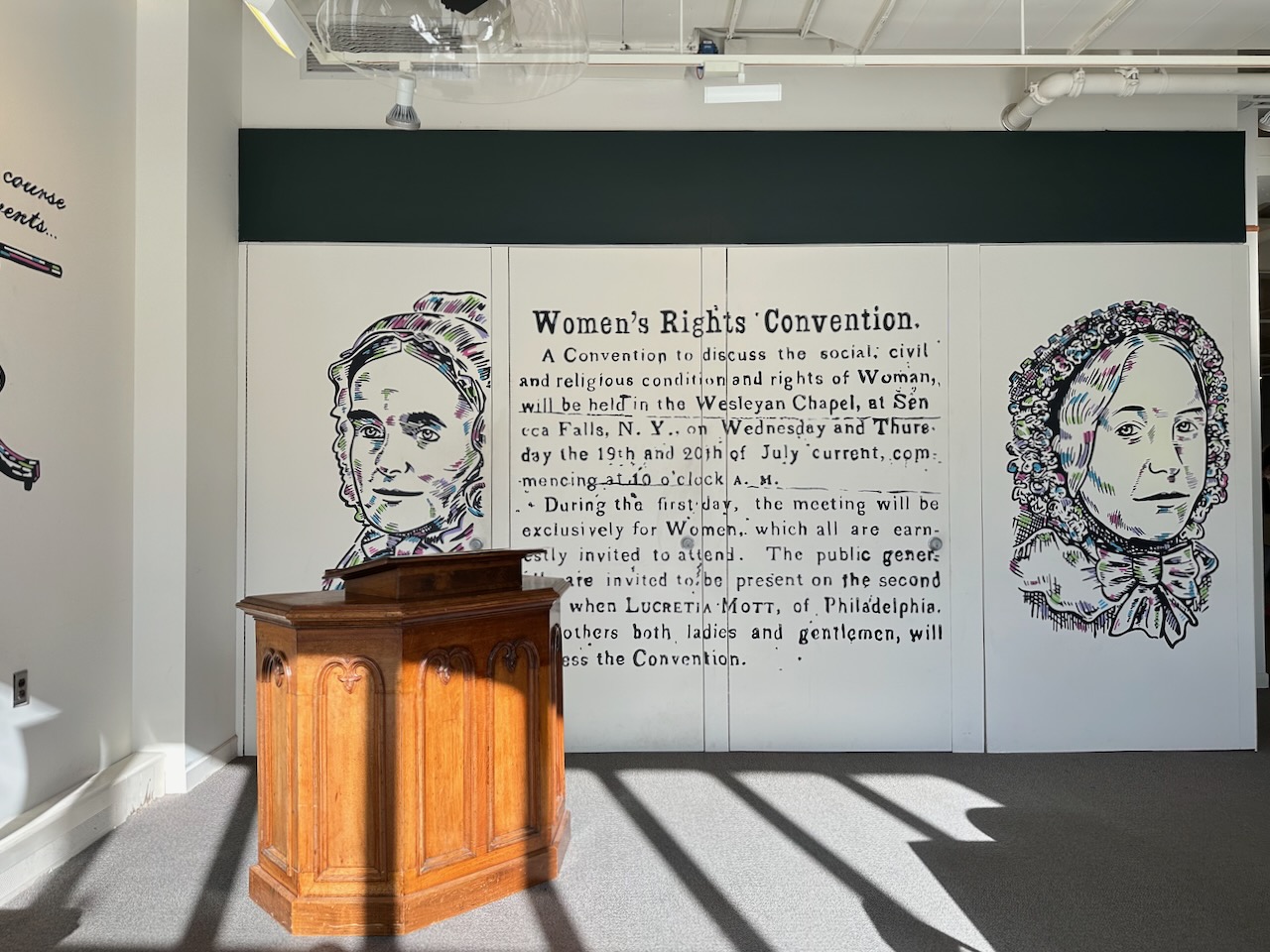 Pulpit in front of wall mural with information regarding Women's Rights Convention.