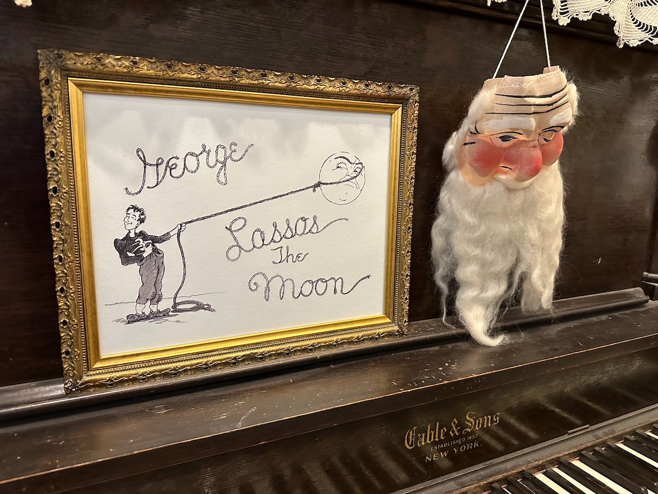 Drawing of GEORGE LASSOS THE MOON from the film, along with a piano and a Santa Mask.
