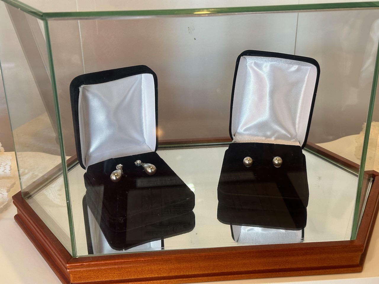 Two pairs of silver earrings in jewelry boxes on display.