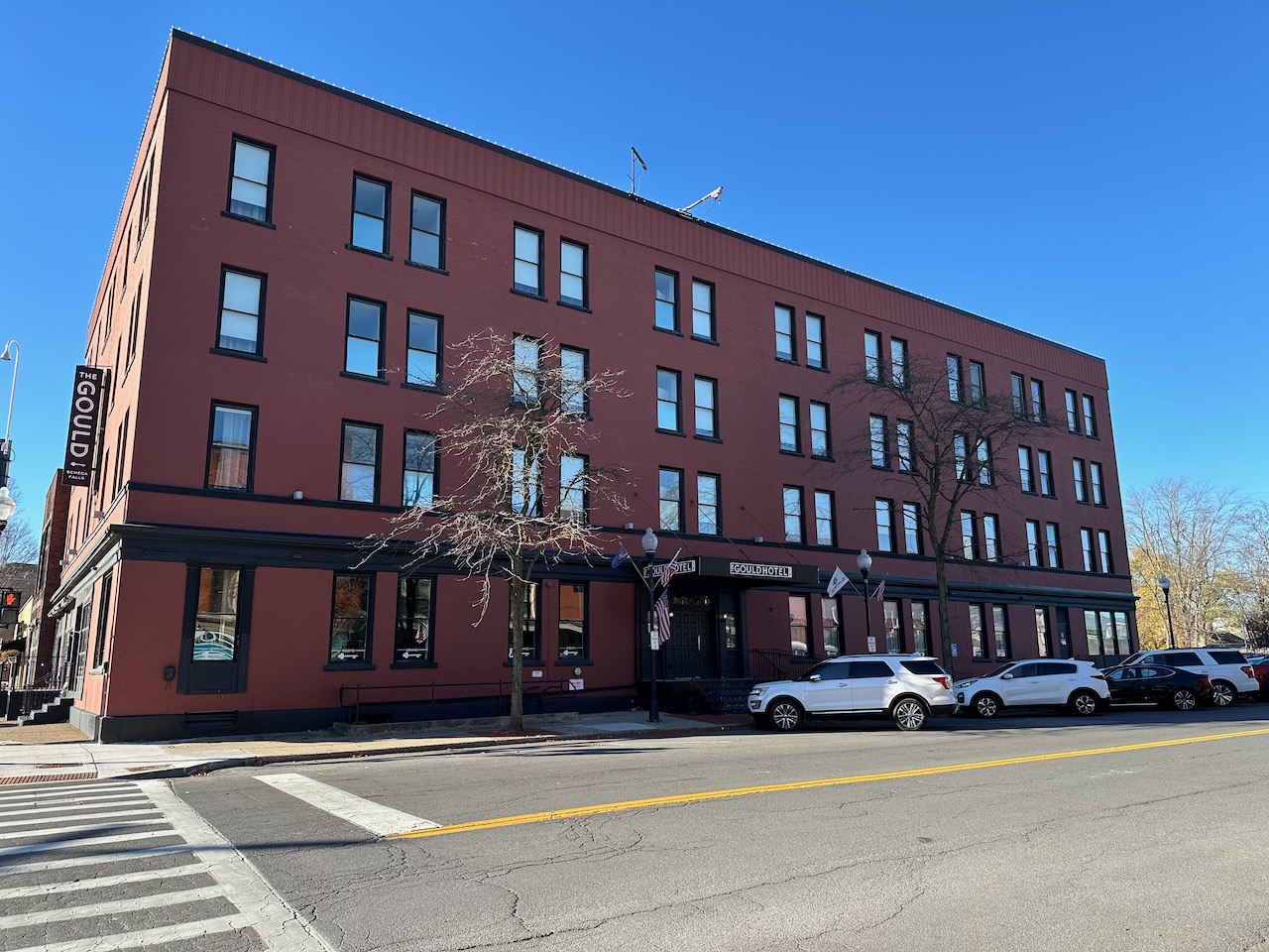 Exterior of Gould Hotel in Seneca Falls. Cars are parked in the street in front of the three-story brick building.