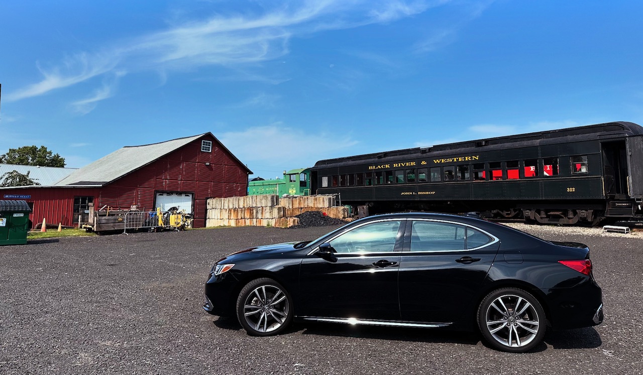 2020 Acura TLX parked in front of old train and train maintenance buildings.