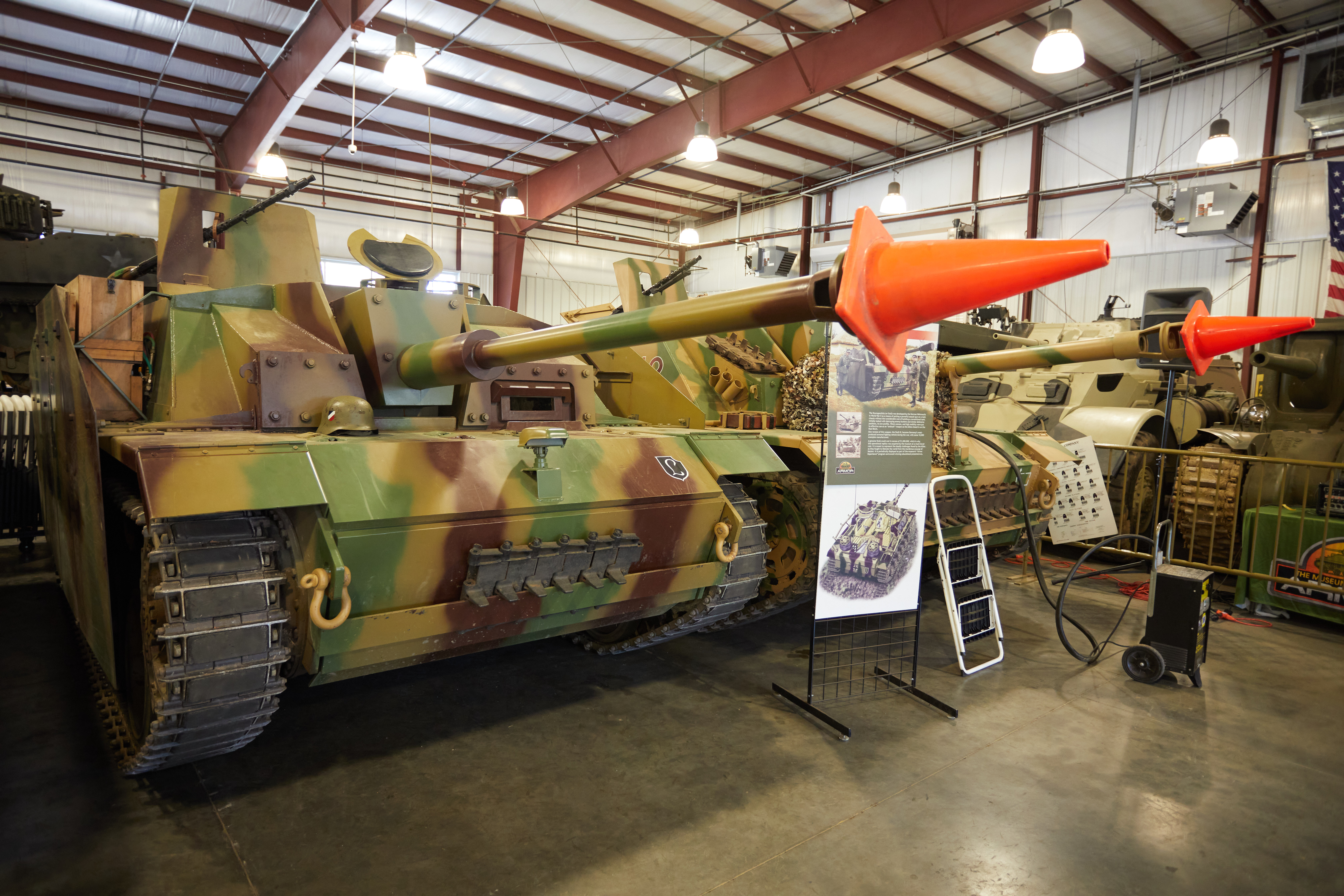 Two Sturmgeschutz assault guns on display. Both have orange cones over their gun barrels.