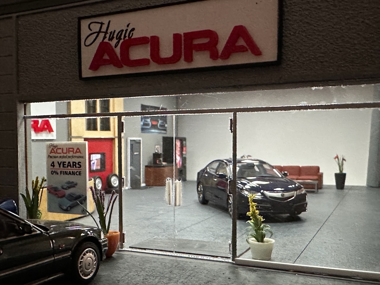 Exterior of Hugie Acura, with Acura TLX on showroom floor.