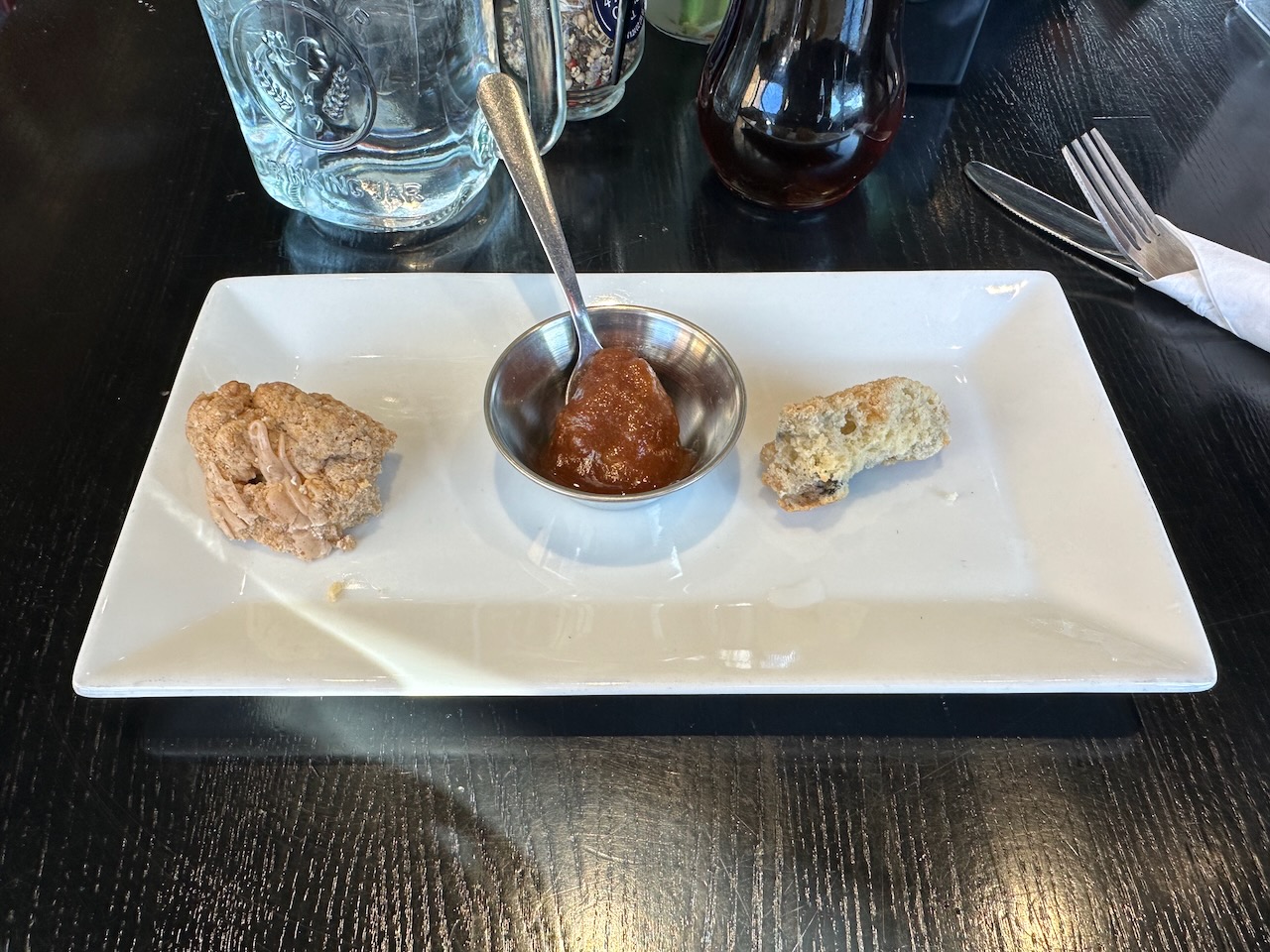 Scone and apple butter on white plate.