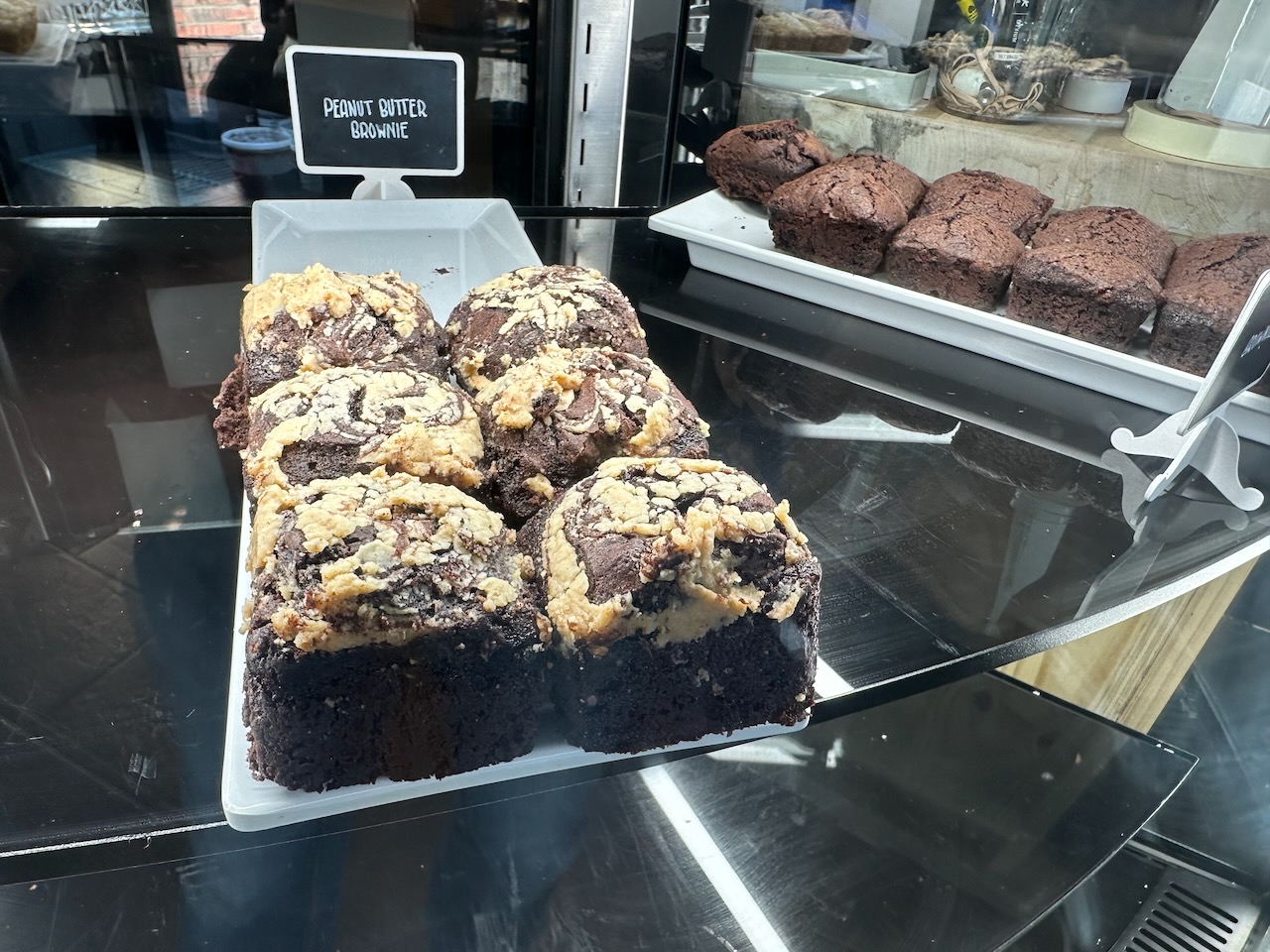Peanut butter brownies on white platter, on display in glass case.