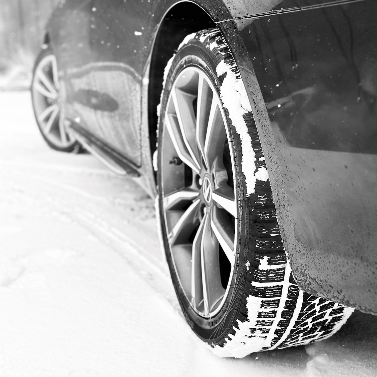 Close-up view of left rear wheel of Acura TLX with Nokian WR G4 tire. Snow is on the ground and the tire. 