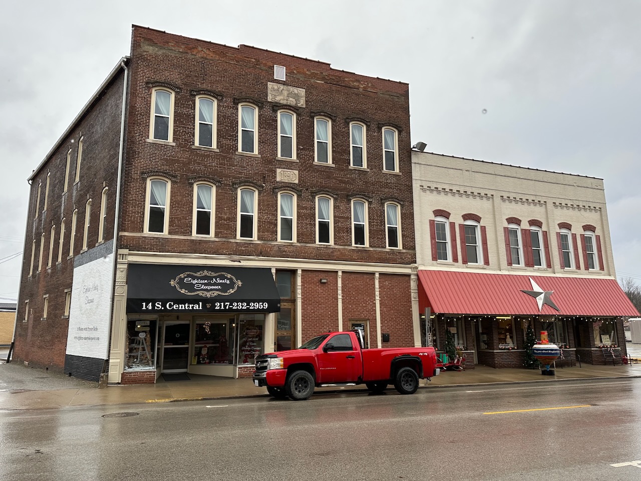Exterior of Eighteen-Ninety Sleepover, a three-story brick building. A red truck is parked in street in front of building.