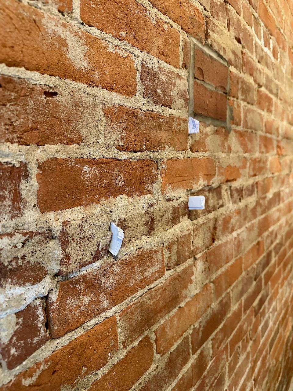 Small pieces of paper tucked into brick wall.