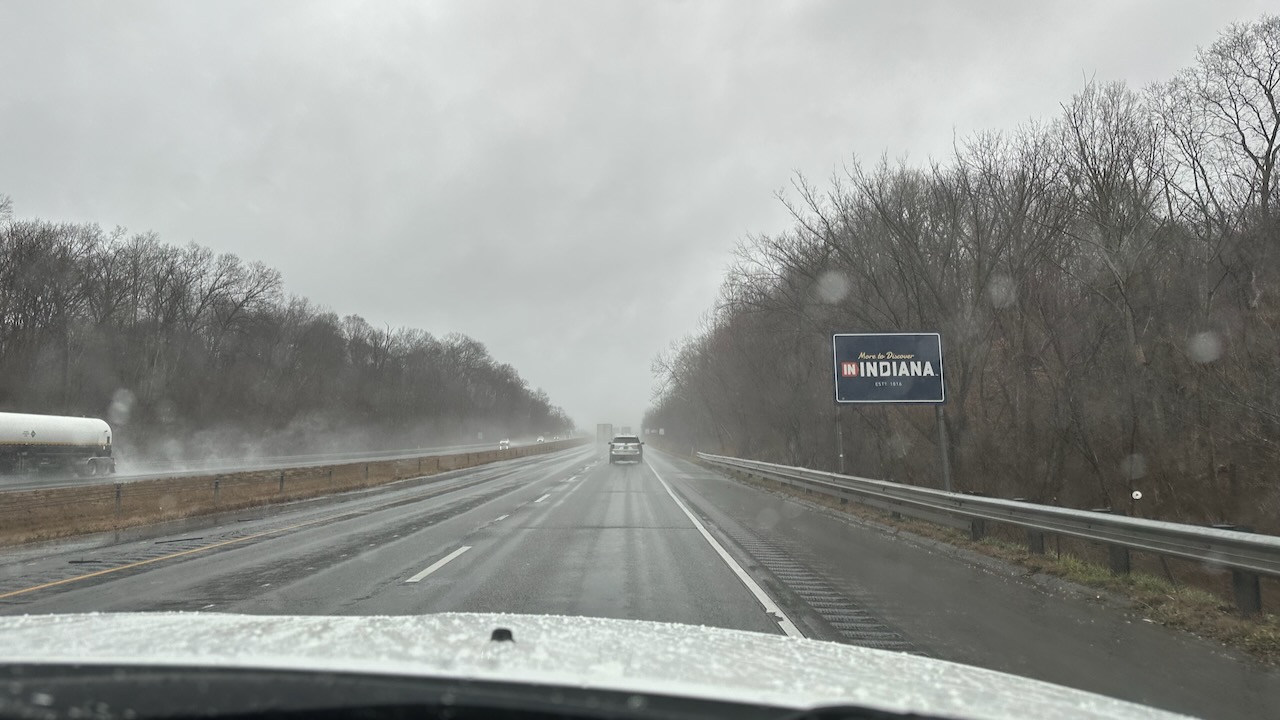 Welcome to Indiana sign along side of I-70. It is raining.