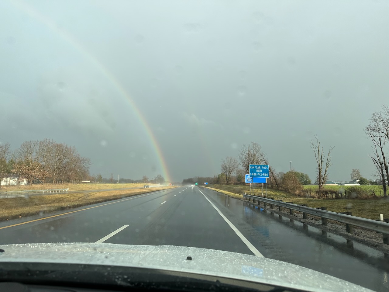 Rainbow in sky over I-70. The roadway is wet.