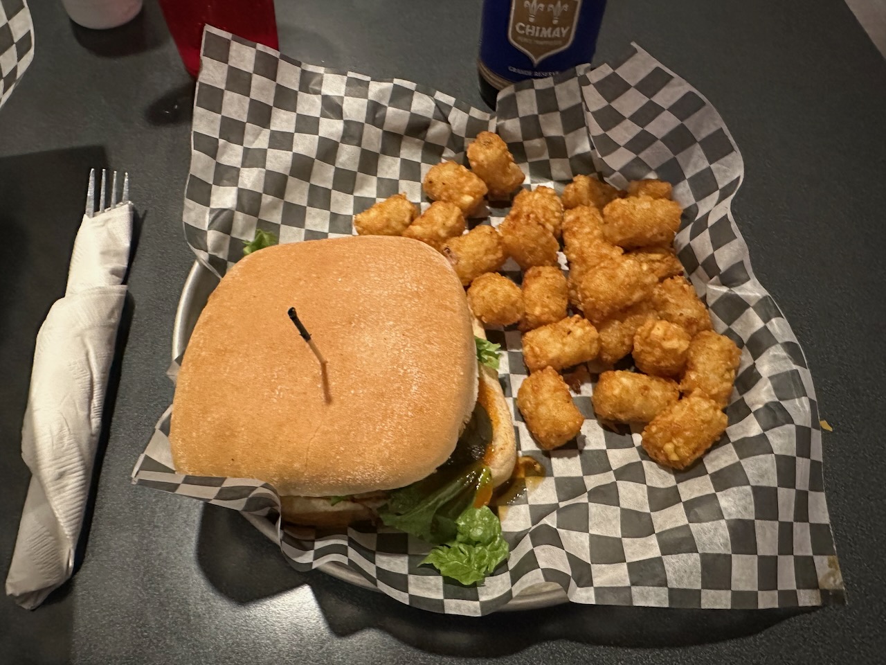Chicken sandwich and tater tots in basket.