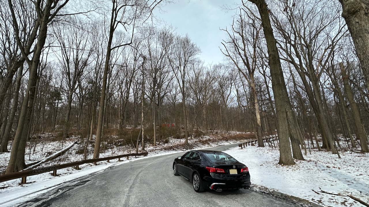 2020 Acura TLX parked on side of Duryea Drive. Snow covers the ground on either side of the tree-lined road. 