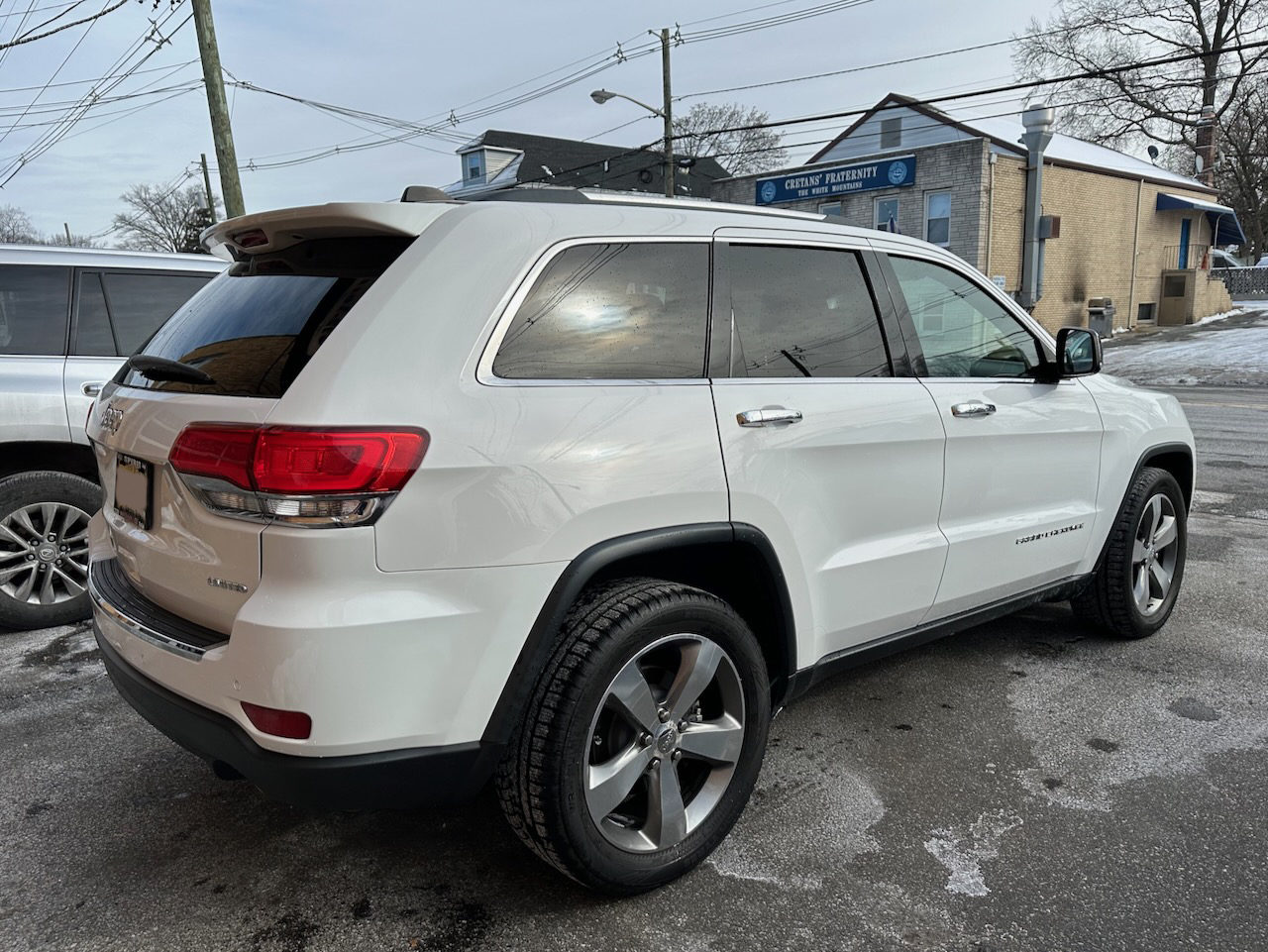 Rear 3/4 view of Jeep Grand Cherokee in parking lot. 