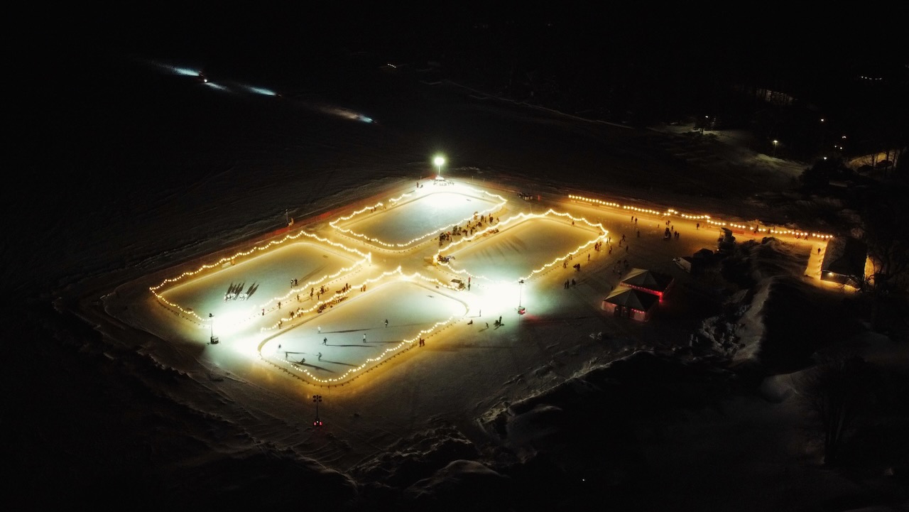 Nighttime view of rinks, illuminated by a series of lights. 