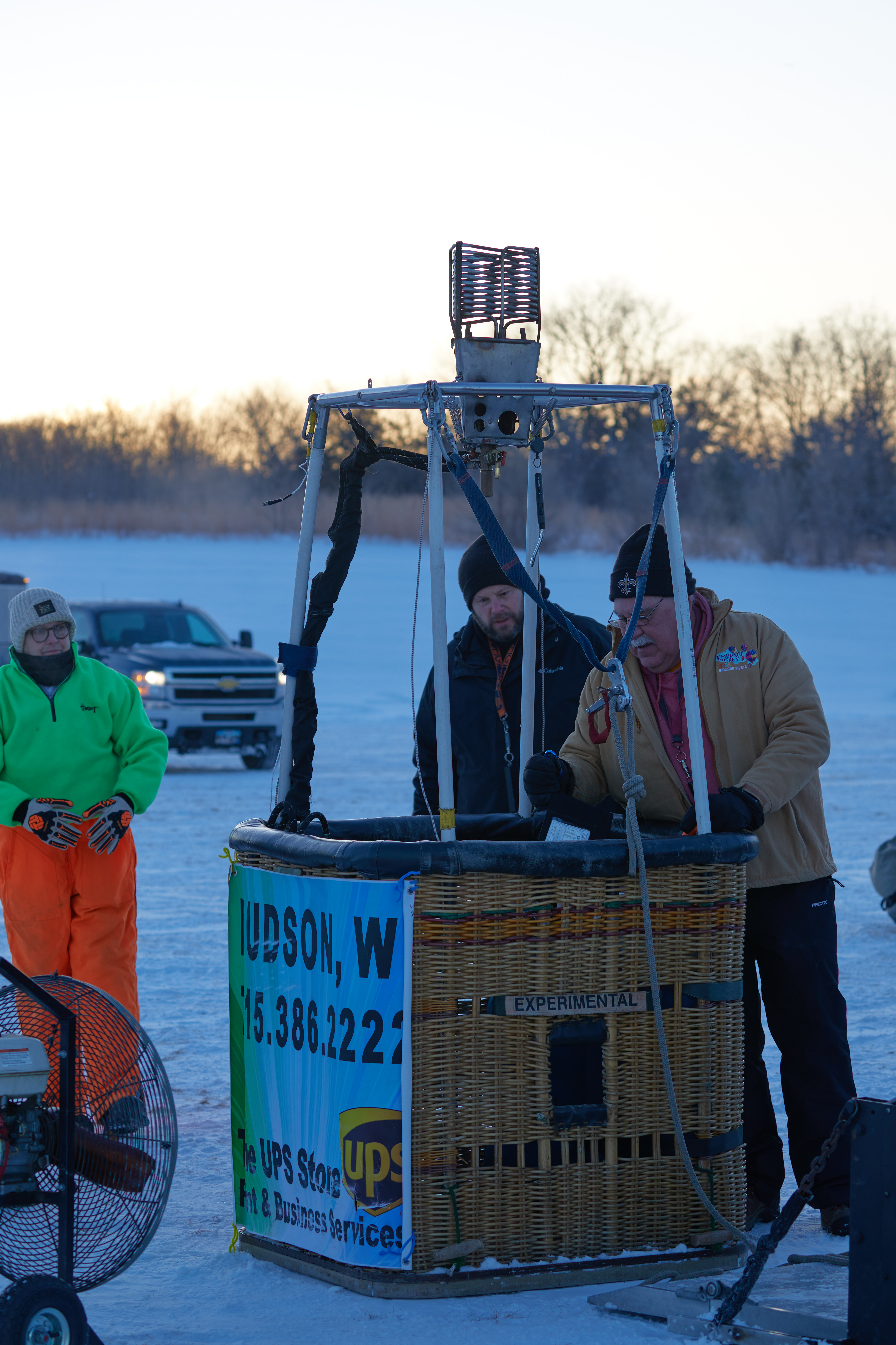 Three men gathered around hot air balloon basket. 