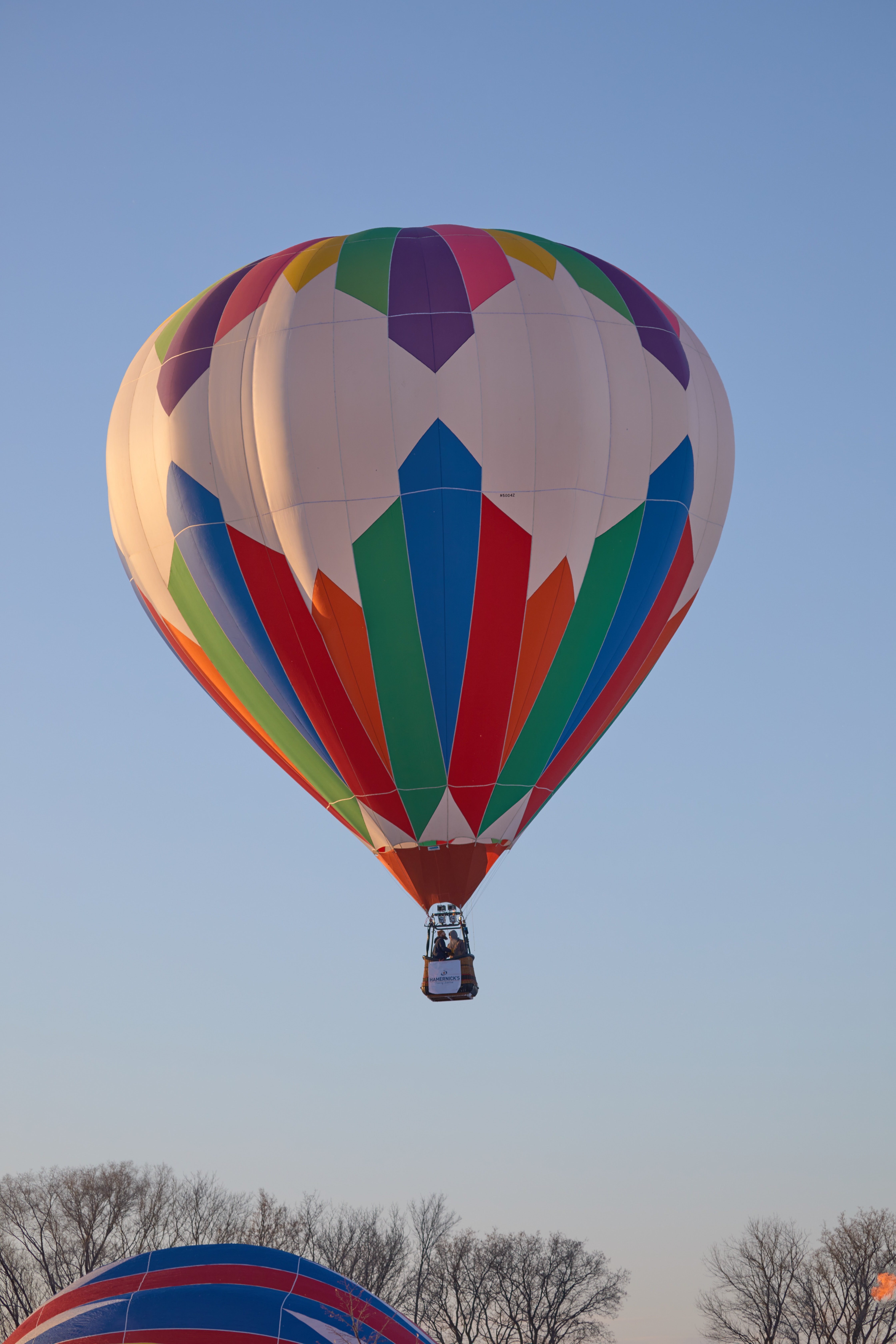White, red, blue, and green balloon lifting off. 