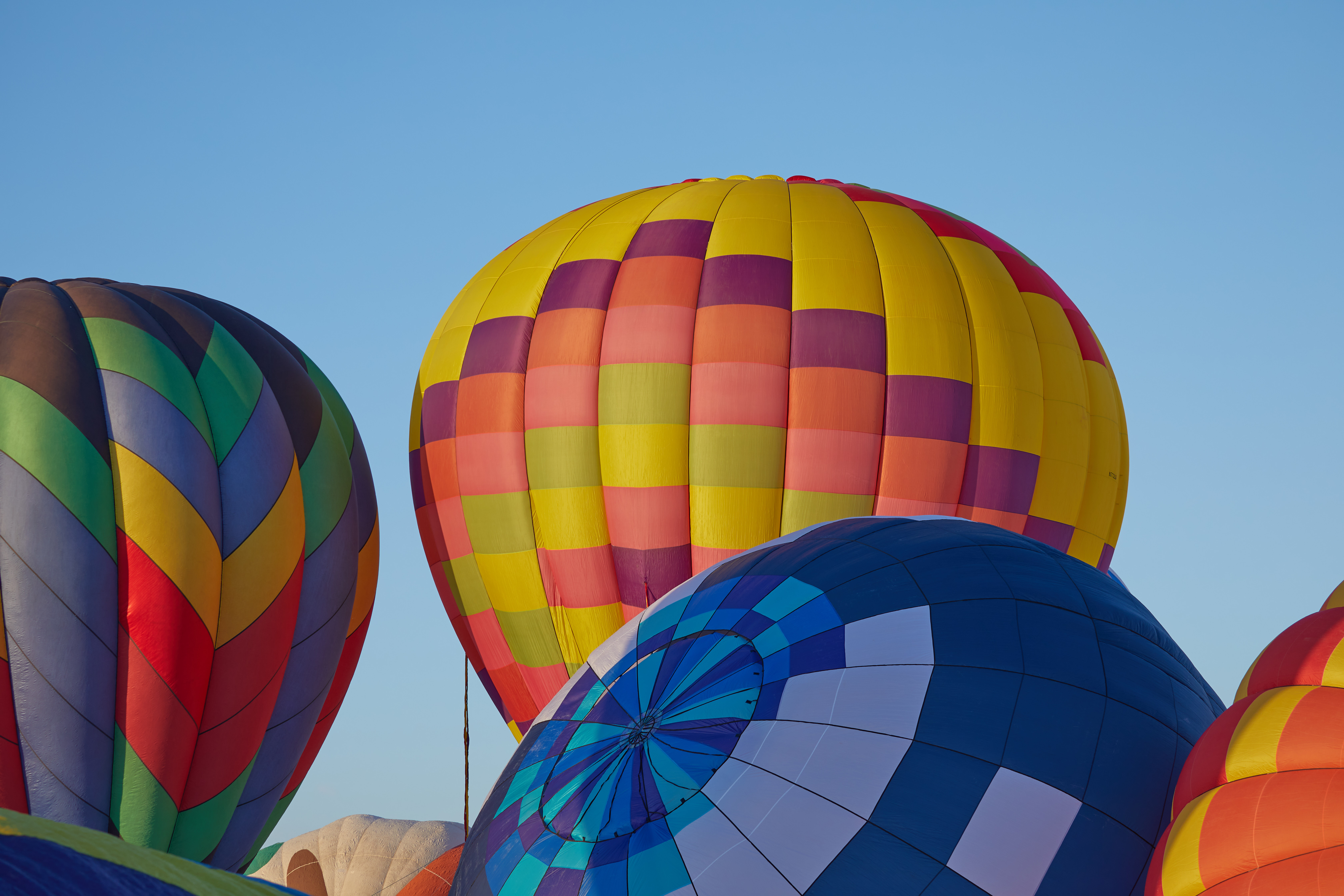 One balloon beginning to lift off in background, with three balloons in foreground. 