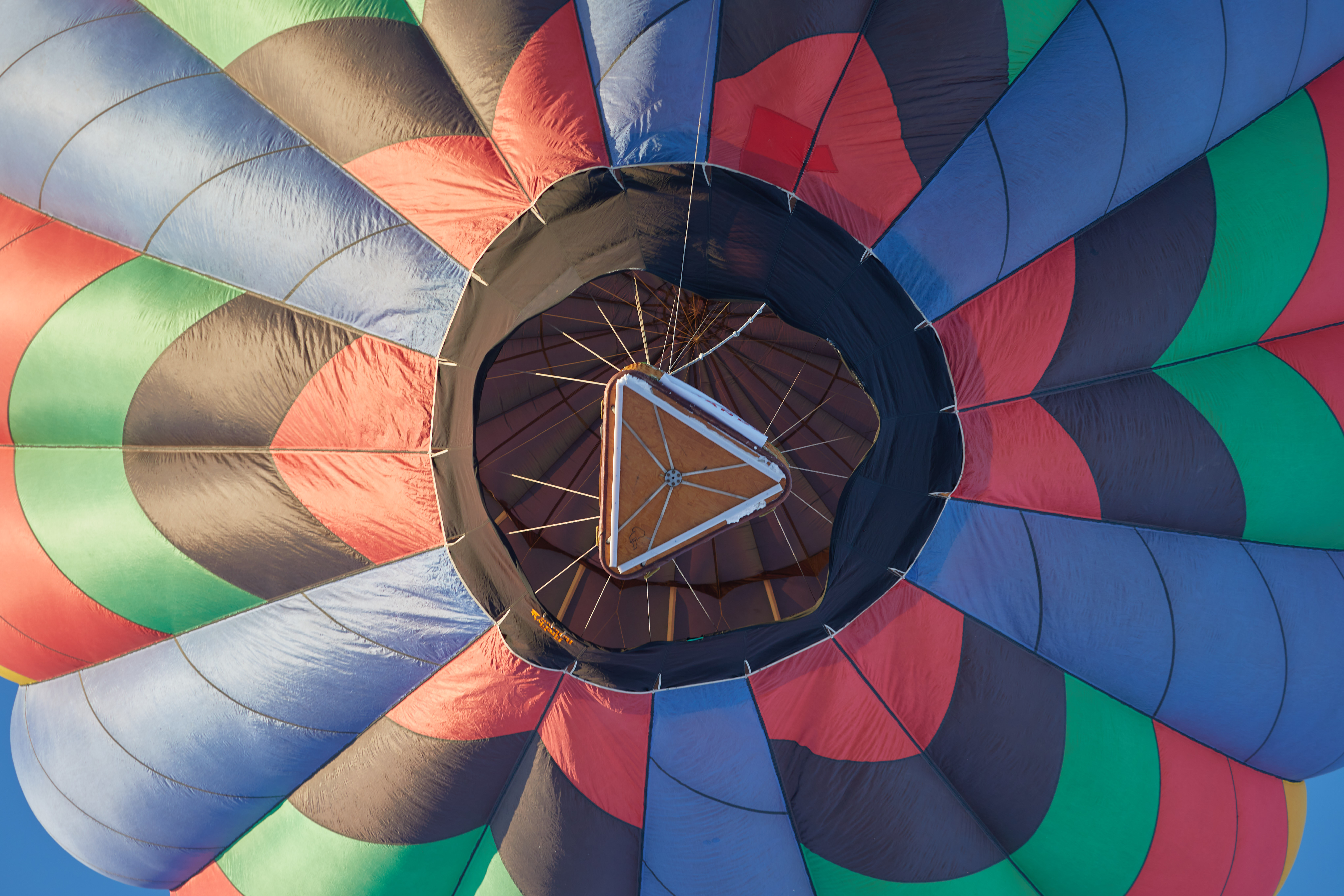 Upward view of bottom of balloon basket and balloon. 