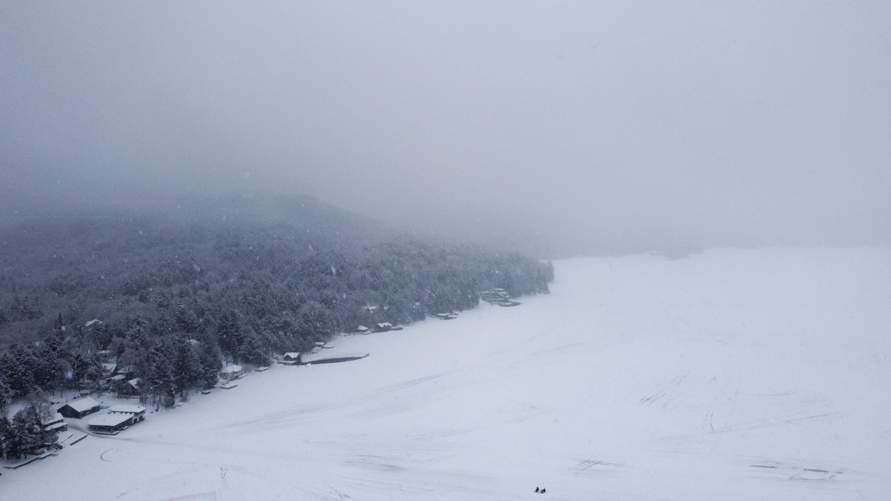 View of shore of Fourth Lake, with snowstorm above.
